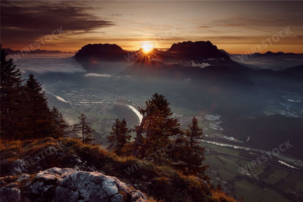 A bird's eye view of a townscape under a misty cloudy sky in the sunset