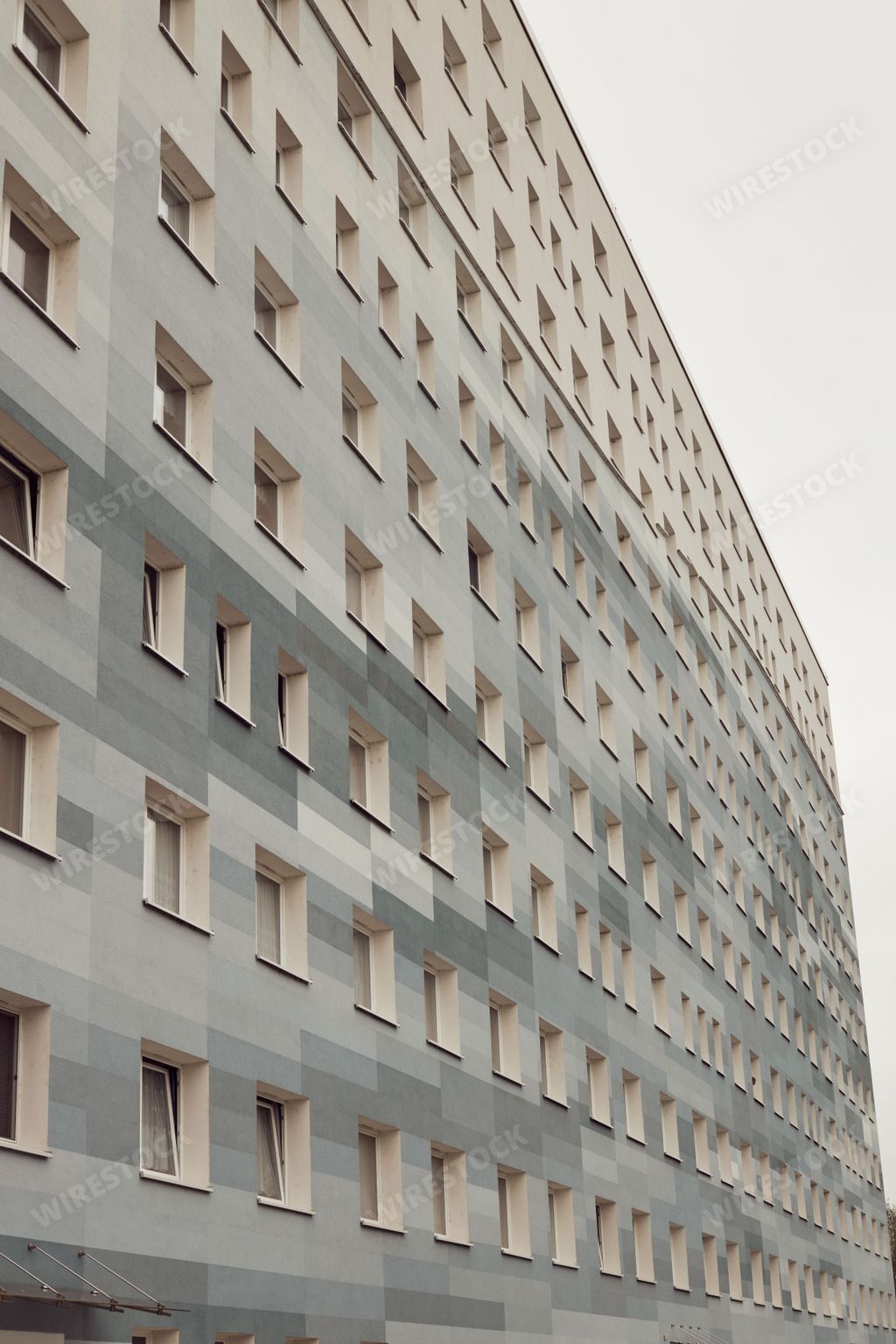 A vertical shot of a modern gray apartment building with square windows at daylight