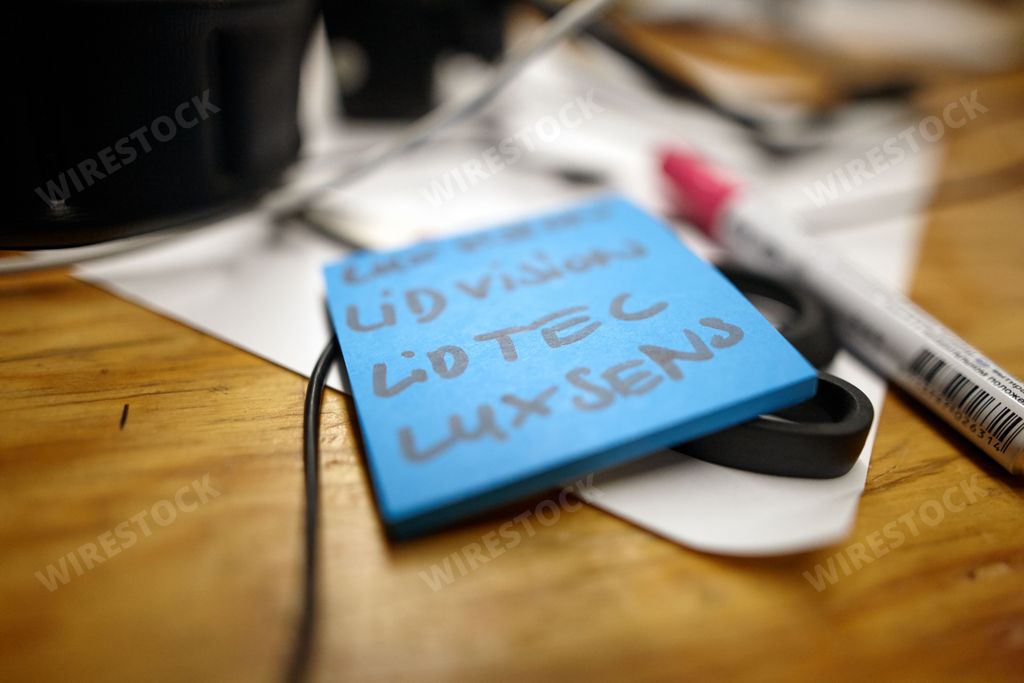 A closeup shot of a blue sticky note with text beside a marker on a table