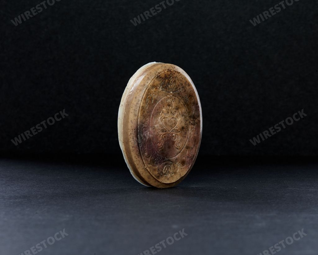 A closeup of a round coffee soap against a dark background