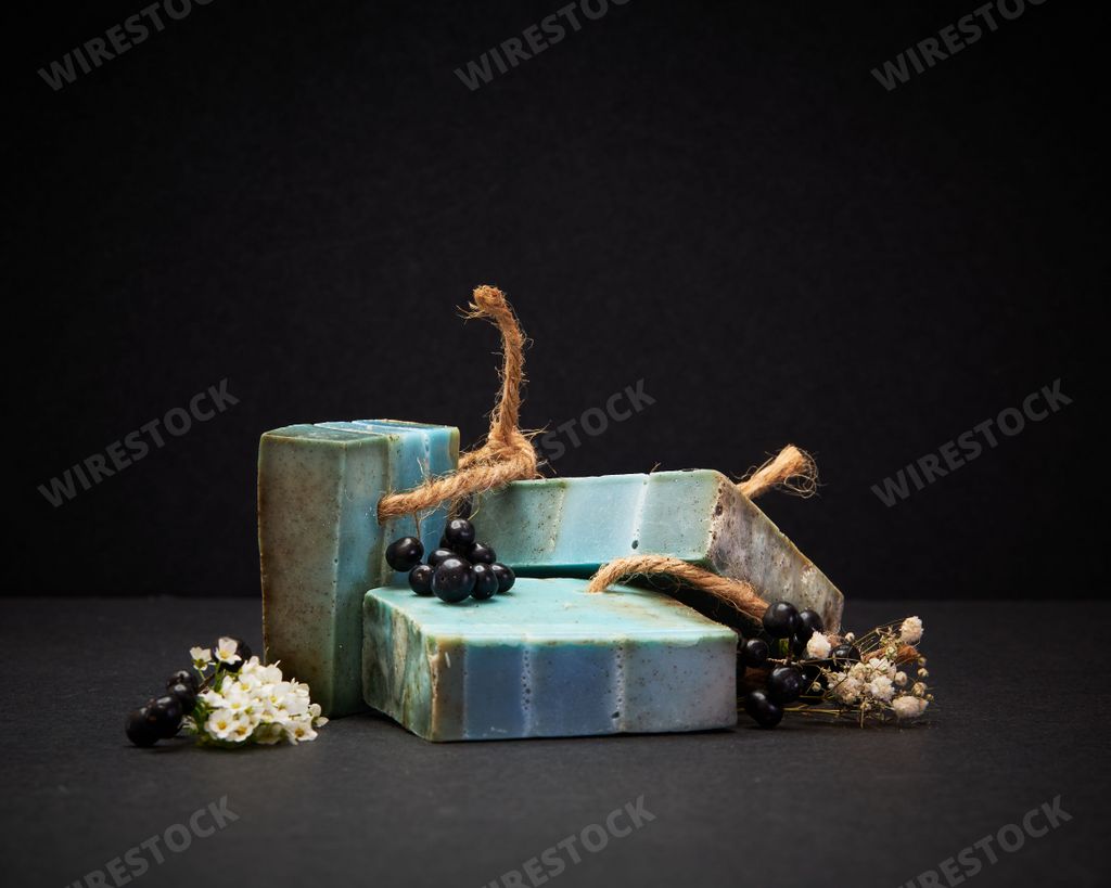 A closeup of herbal soap bars with flowers against a dark background