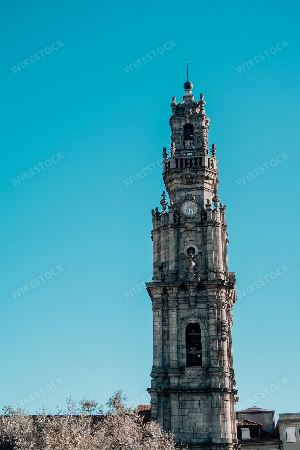 A vertical shot of a weathered church tower in a bright blue sky in Porto, Portugal
