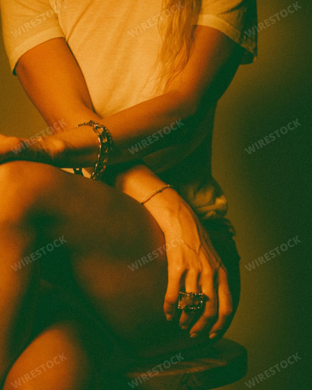 A Pretty Female wearing jewelry sitting legs crossed with short skirt and orange light