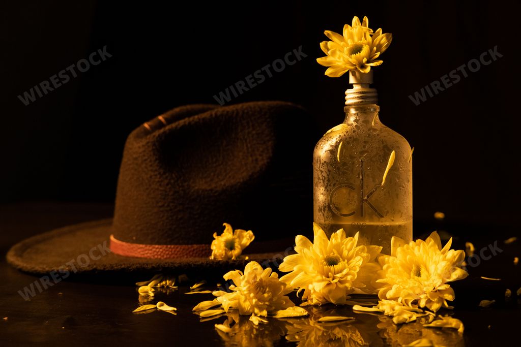 A bottle of the Calvin Klein Cologne For Men perfume with yellow flowers on a black background