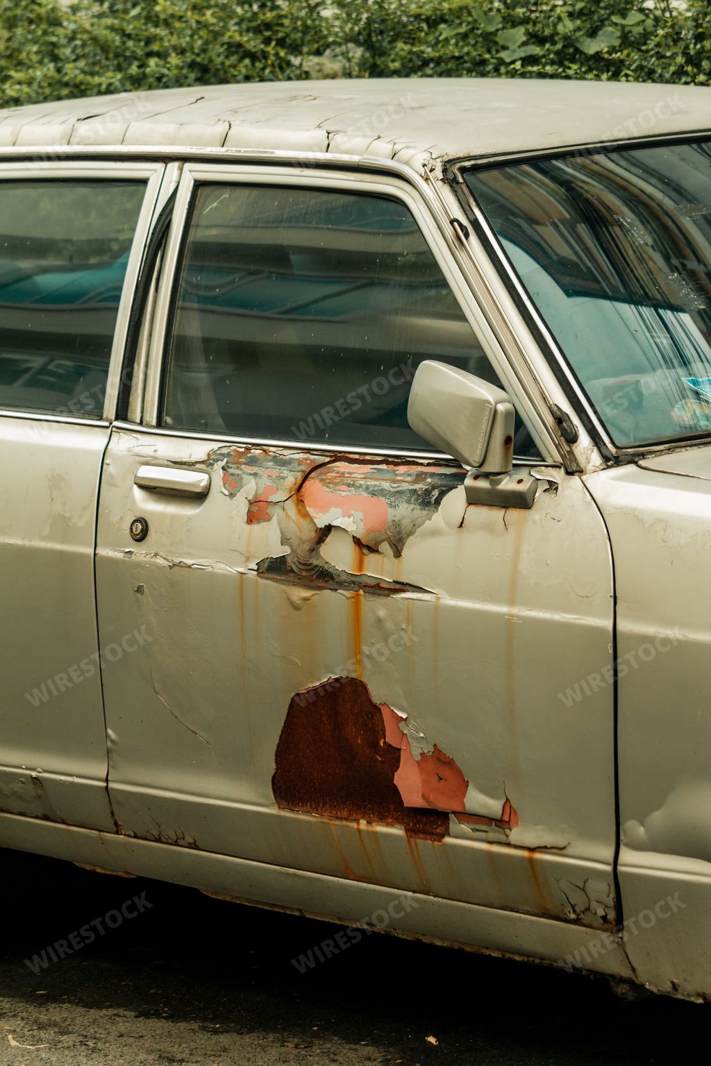 A vertical shot of a rusty broken vintage white car