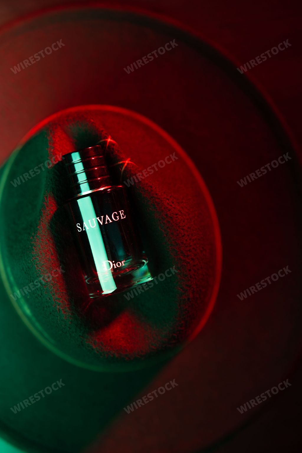 A vertical flat lay of Dior Sauvage Cologne against the leather background with red neon lights