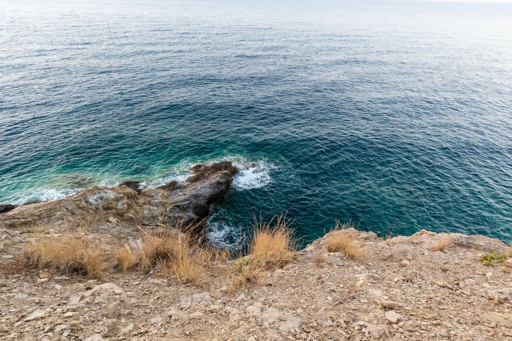 A beautiful view from a top of a rocky cliff on blue water on a sunny day