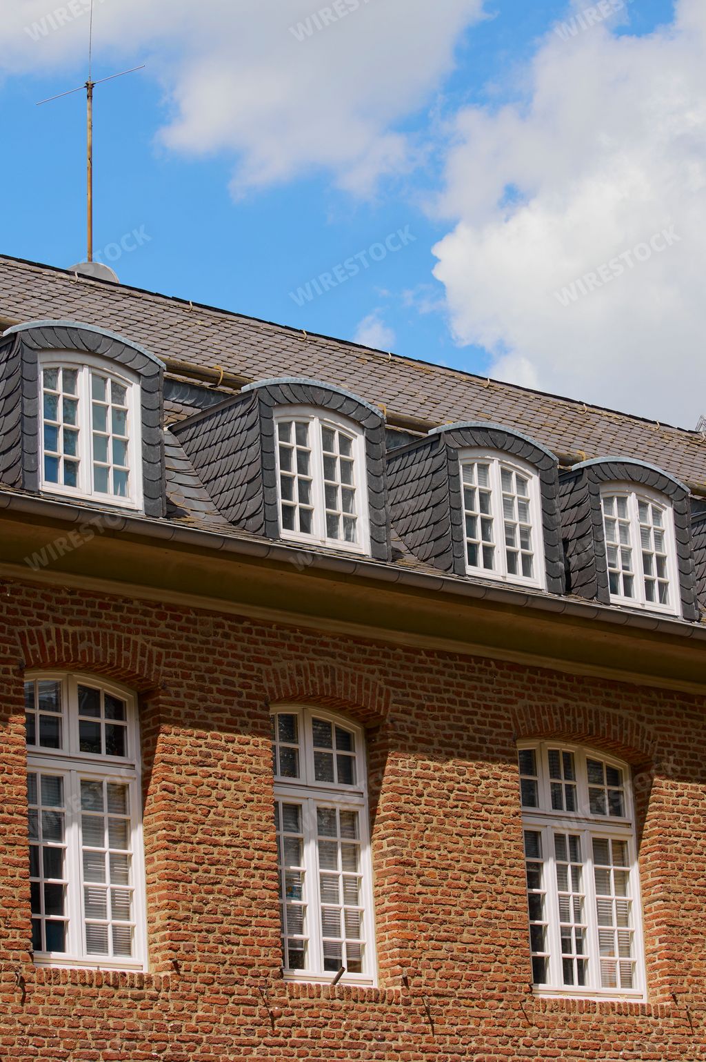 A vertical shot of an old style building exterior with red bricks and tiled roof in the daylight