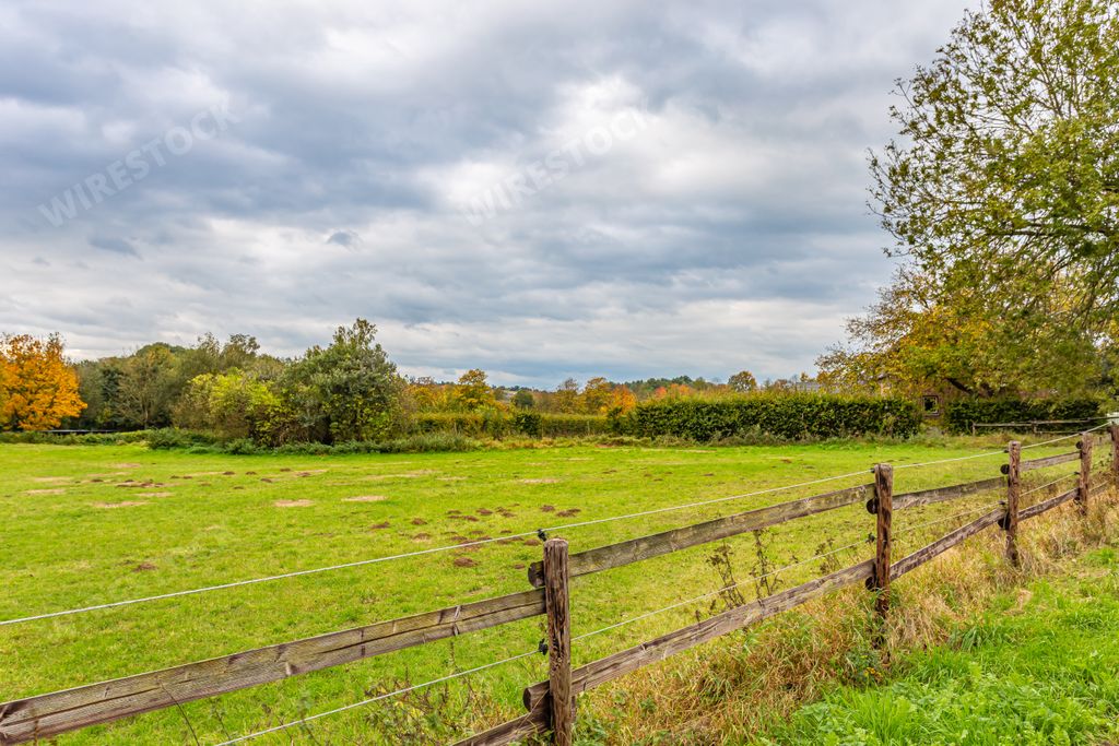 A landscape of wooden fence in the field under a cloudy sky