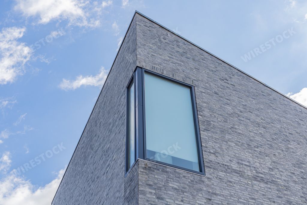 A sharp angle of a modern stone building with a large window in the corner