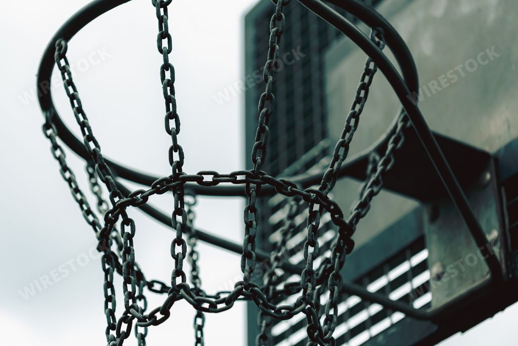 A closeup of a basketball hoop with chain net under the sunlight with a blurry background