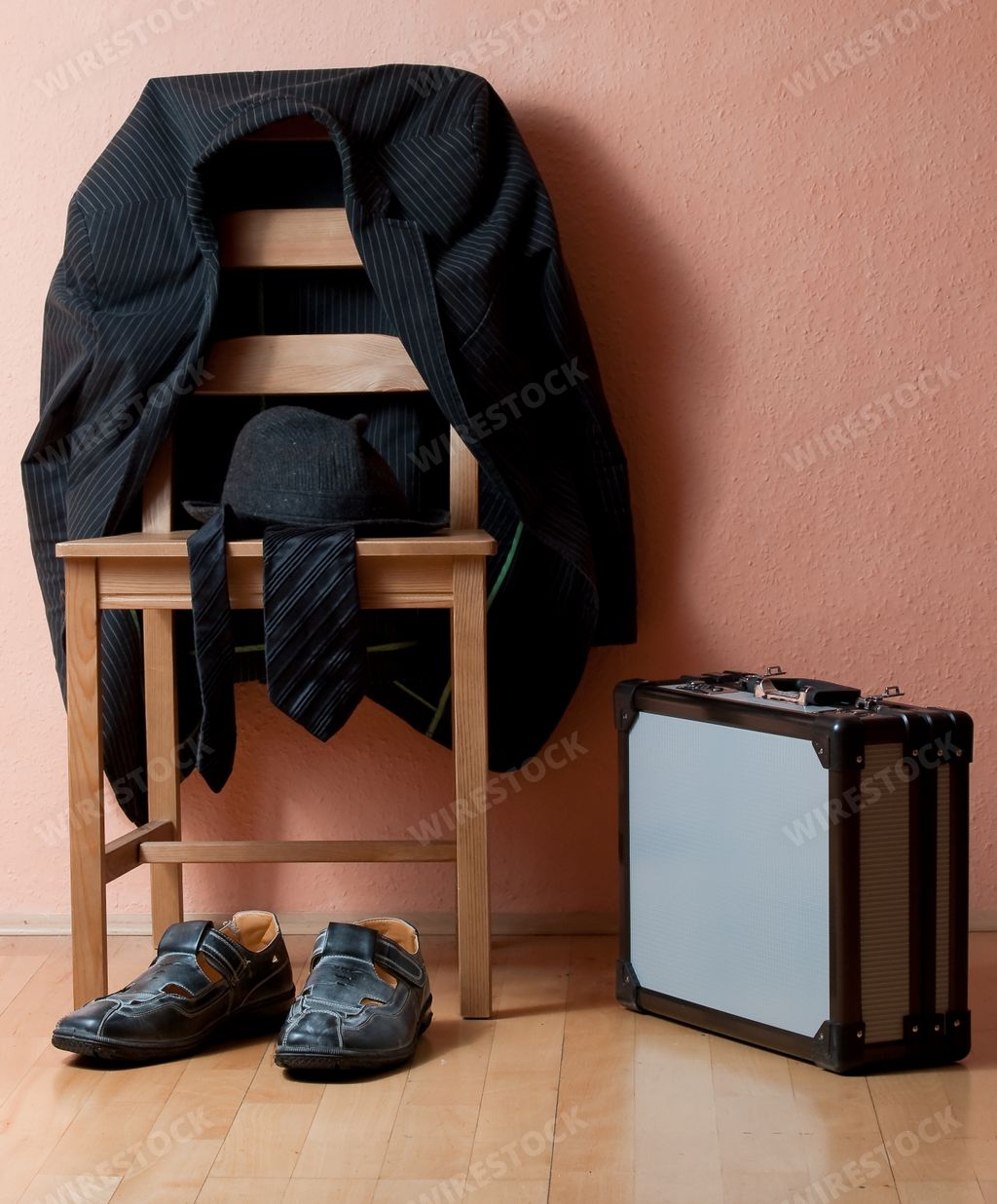 A vertical shot of a suit on the chair next to shoes and a briefcase