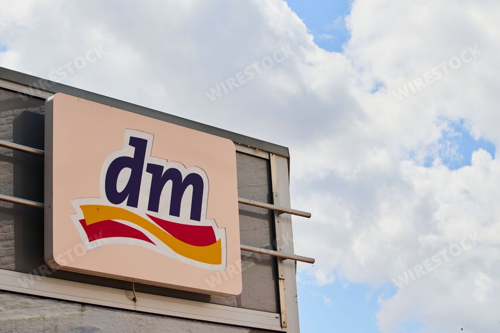 A closeup of a billboard of the dm drugstore against a cloudy blue sky