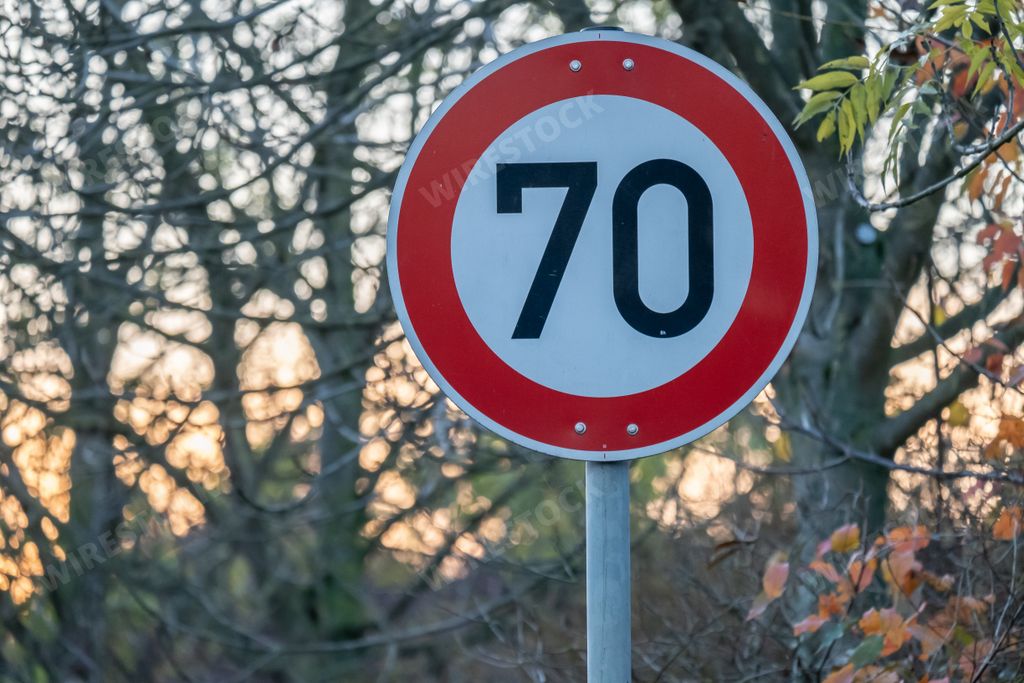 A speed limit sign for 70 km/h near the trees