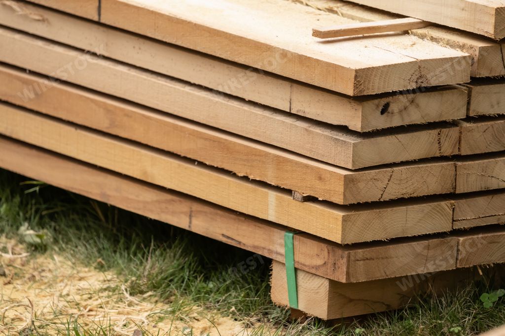 A closeup of a pile of lumber wood on the grassy ground in the garden