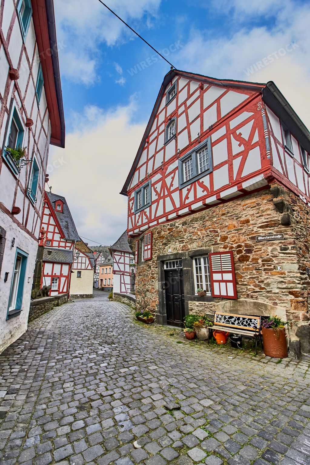 A panoramic shot of the beautiful village Monreal buildings, Germany on a stone floor against a blue cloudy sky