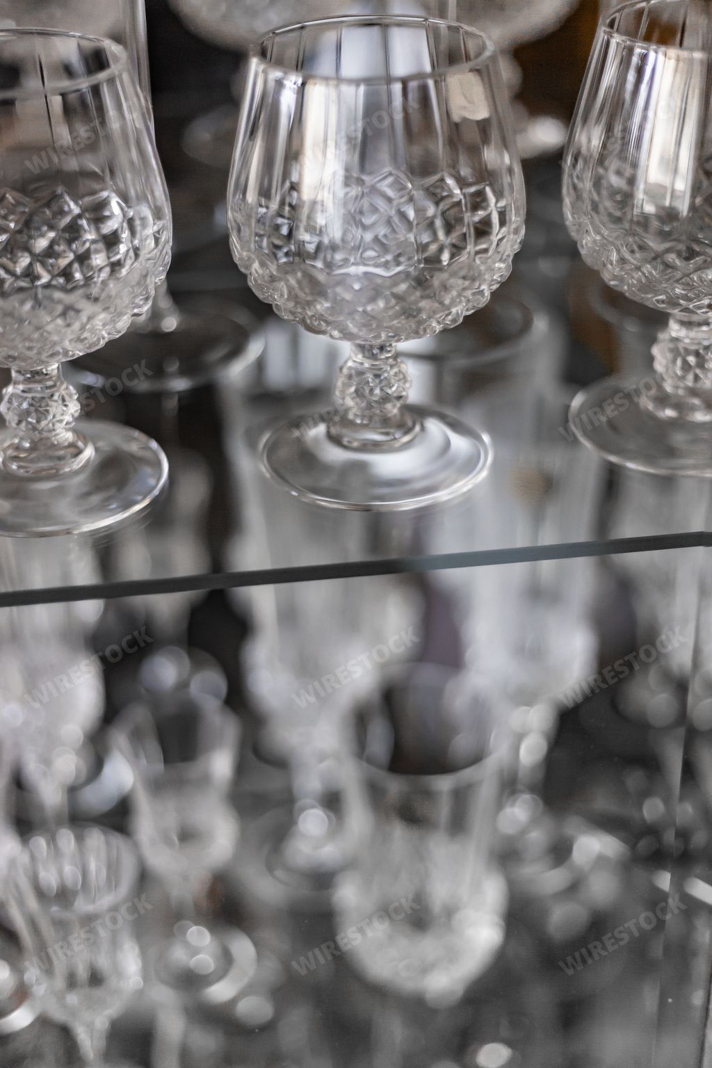 A vertical closeup shot of crystal cognac glasses in a closet
