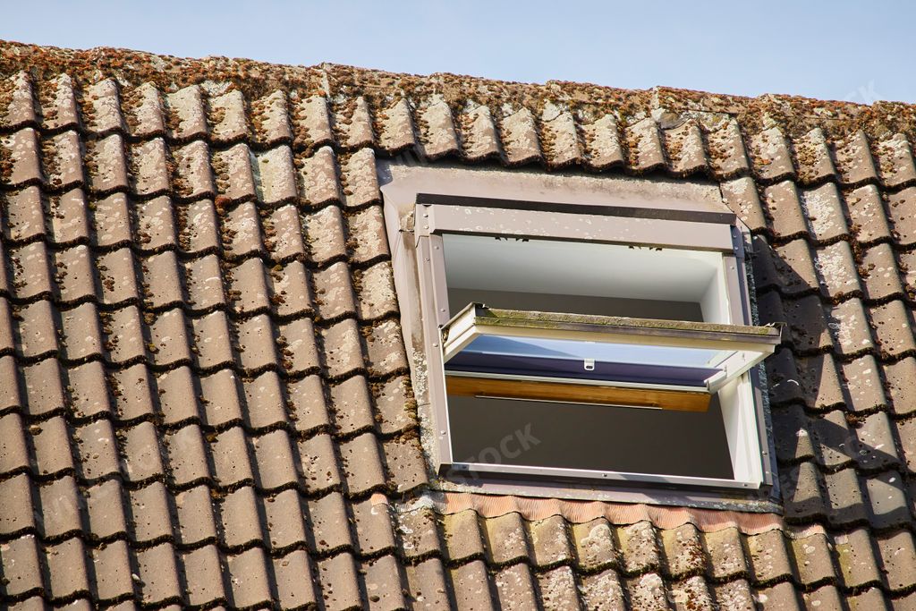 A closeup shot of a roof with brown tiles and an opened skylight window