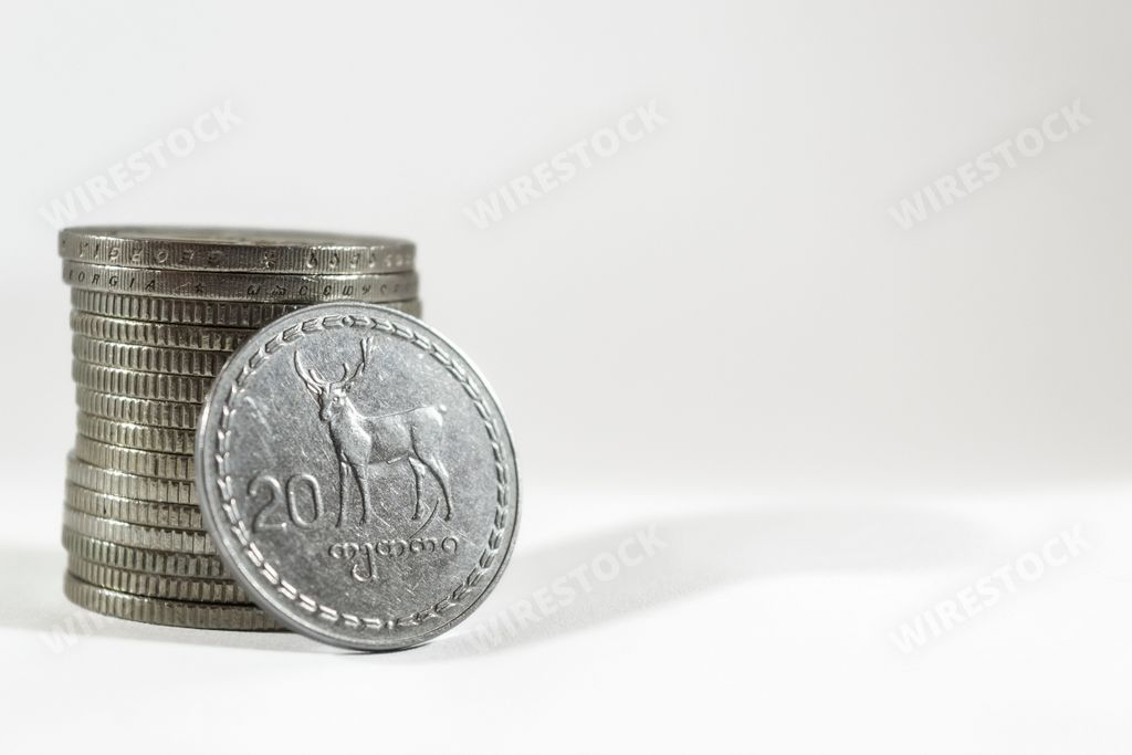 A stack of Georgian Lari coins with a 20 Lari coin leaning on it on a white background