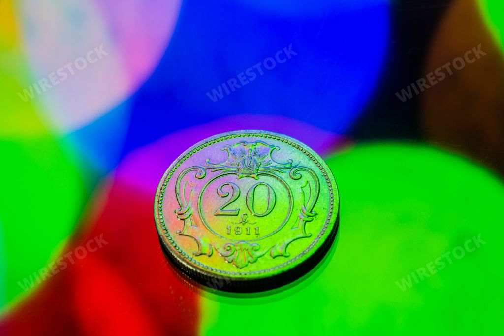 A close-up shot of a ten cent coin illuminated by a vibrant array of colorful lights