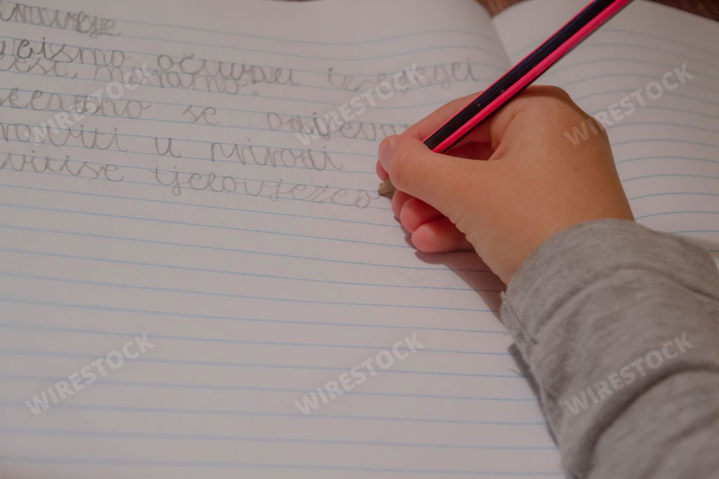 A close-up of a hand holding a pencil and writing on a blank piece of paper, with the focus on the pencil and the hand that is writing