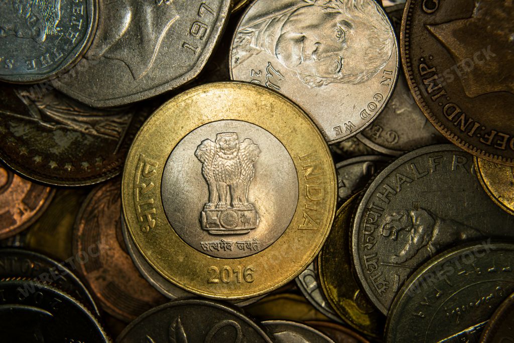 A top view of assorted coins stacked, with rupee coin at the center
