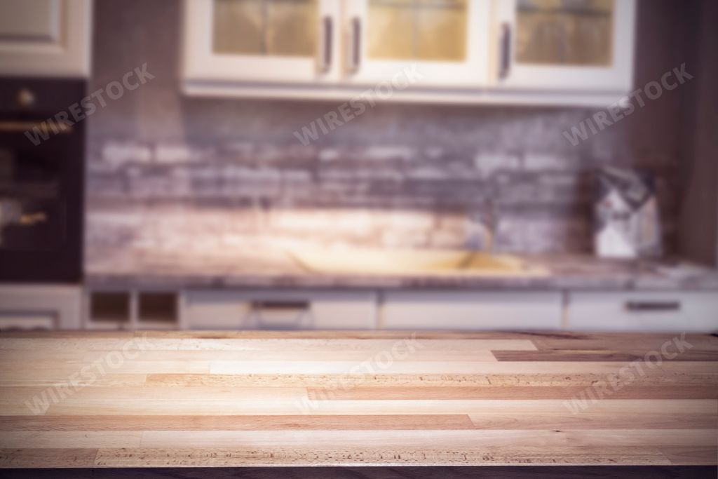 A closeup shot of a wooden table in a kitchen with drawers as a background