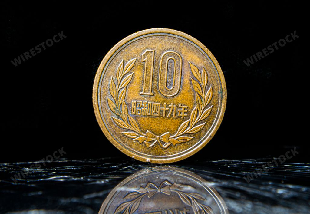An aged penny sitting atop a table, displaying 10 Yen - Heisei, Japanese coin