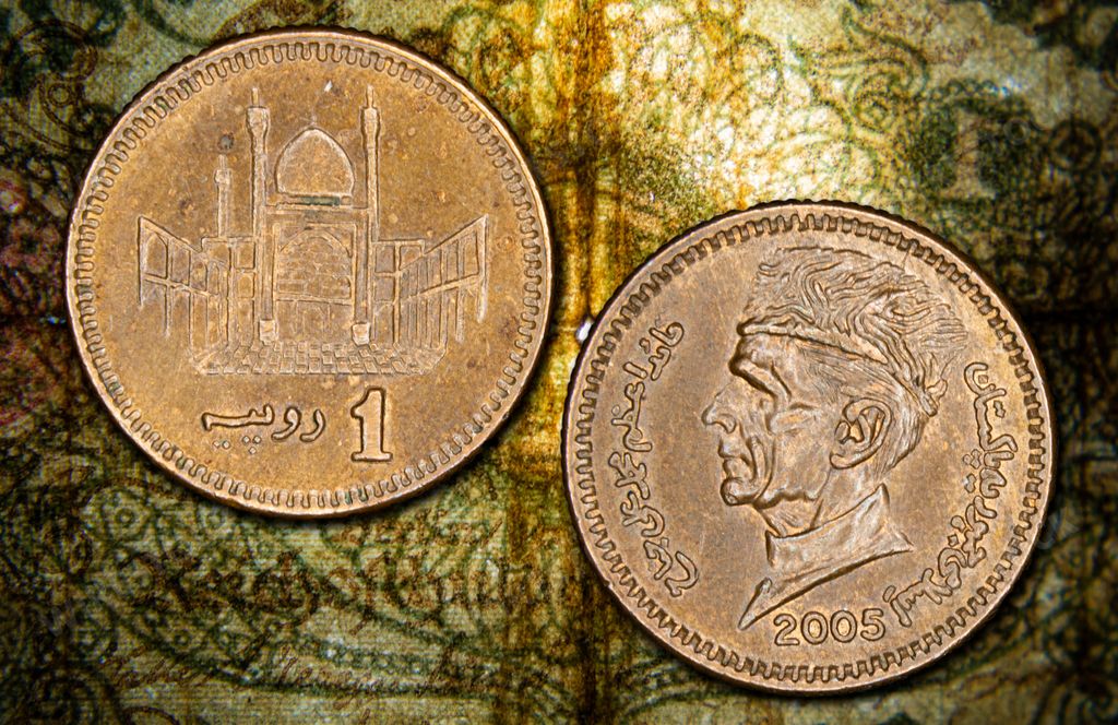 A close-up view of Pakistani 1 rupee coins from 2005 with intricate designs