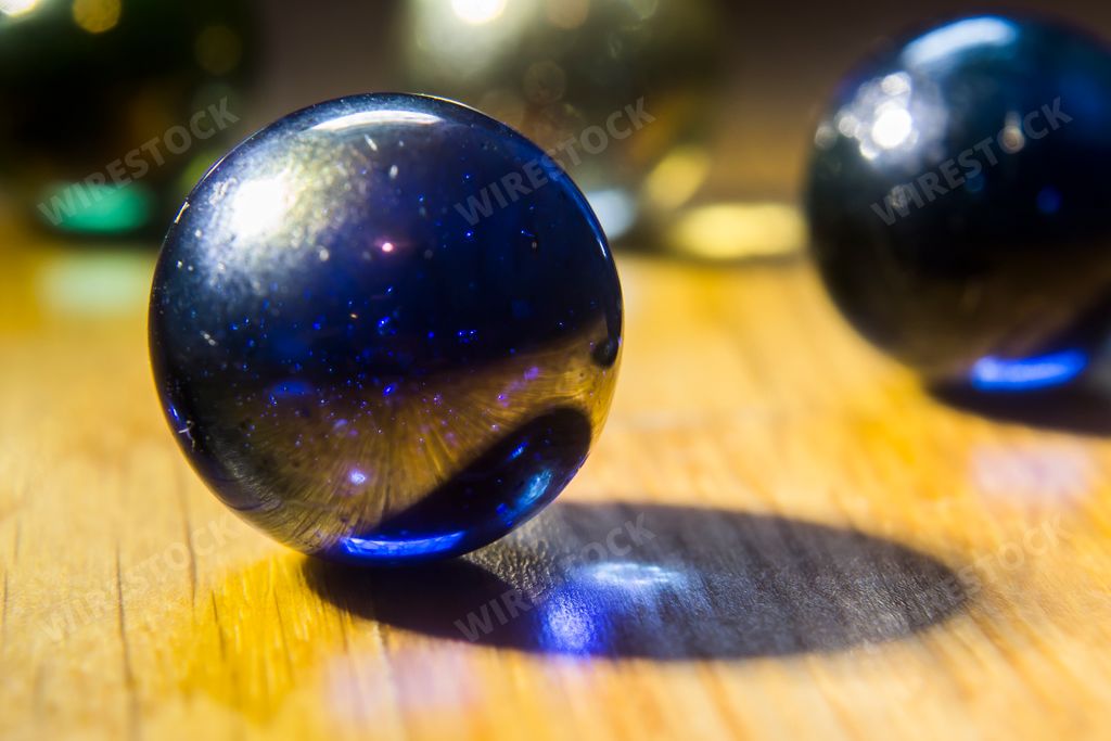 A closeup shot of two dark blue marbles on top of a wooden table
