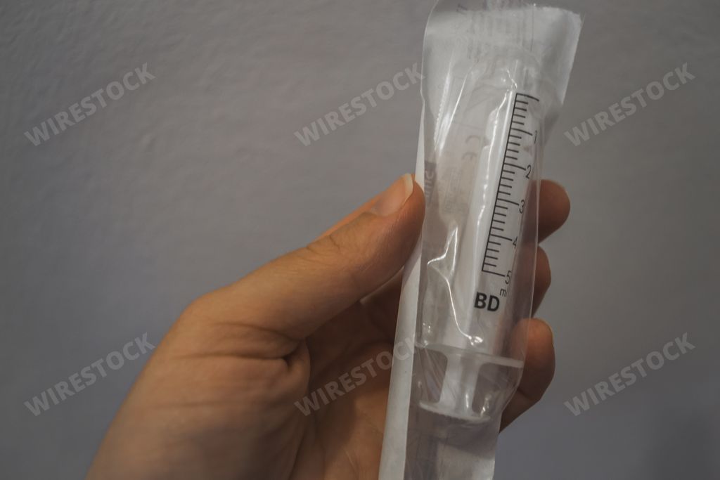 A person holding a medical syringe inside a sealed plastic