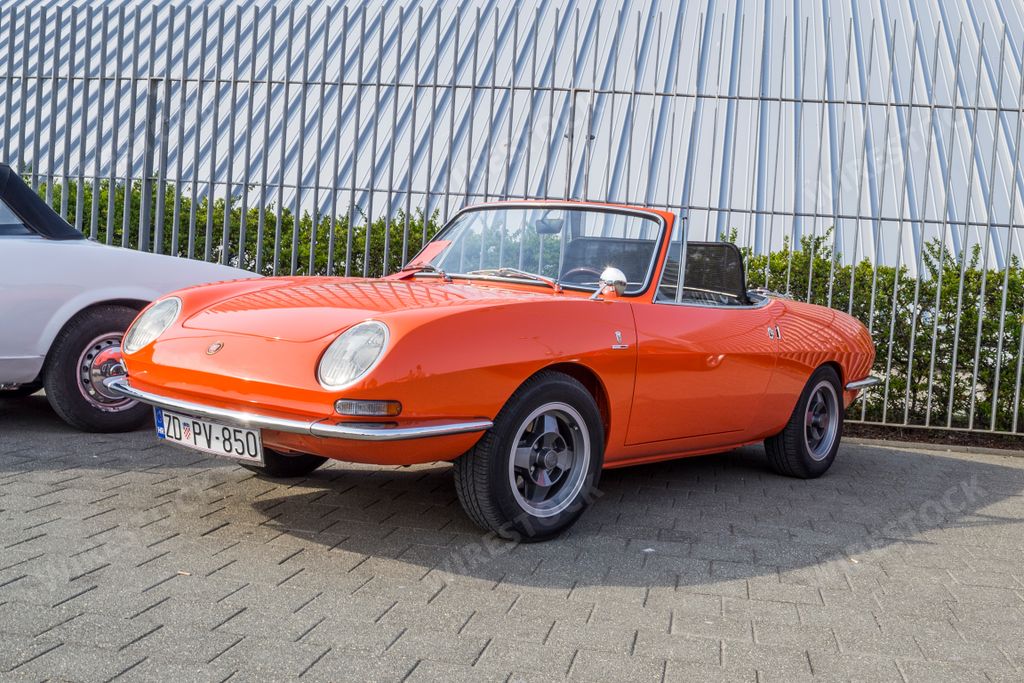 A closeup shot of an orange Fiat 850 sport spider car from the 1970s on a sunny day