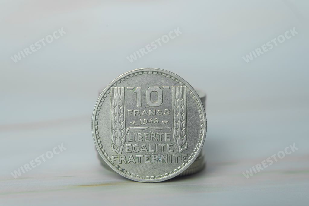 A French 10 francs coin against a pale background