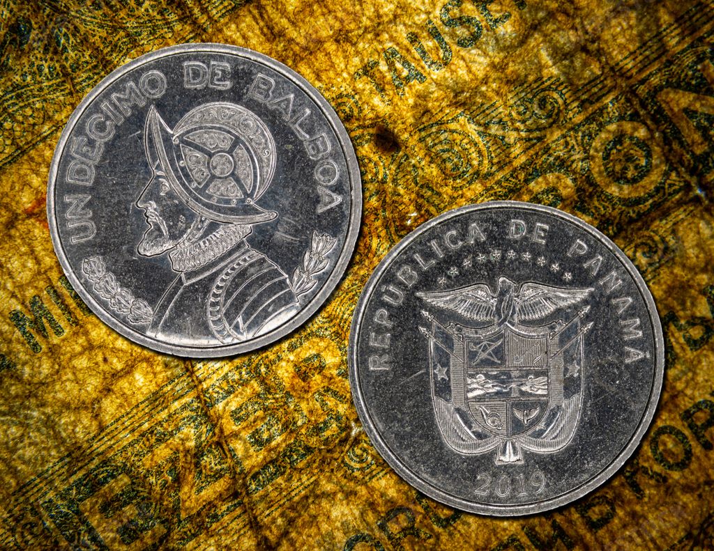 A close-up of two Panamanian coins, one showing Balboa and the other the coat of arms of Panama
