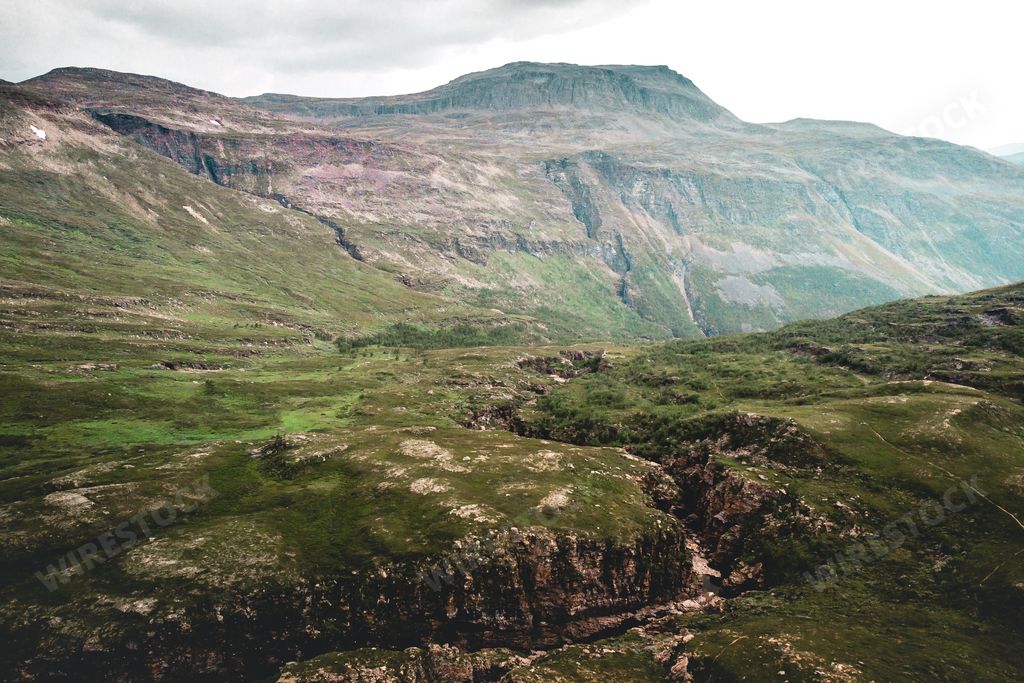 A beautiful landacape view of large green rocky hills against light cloudy sky