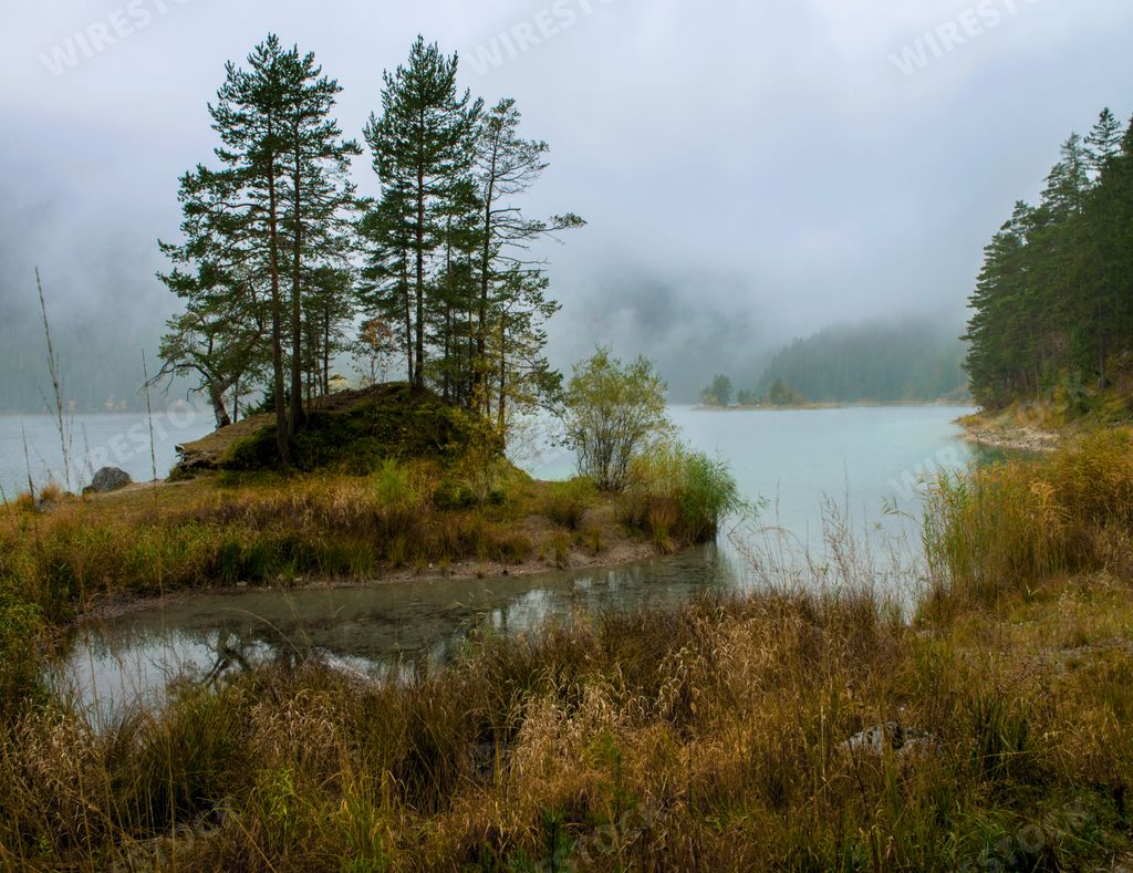 A lake Zugspitze surrounded by forest and fog