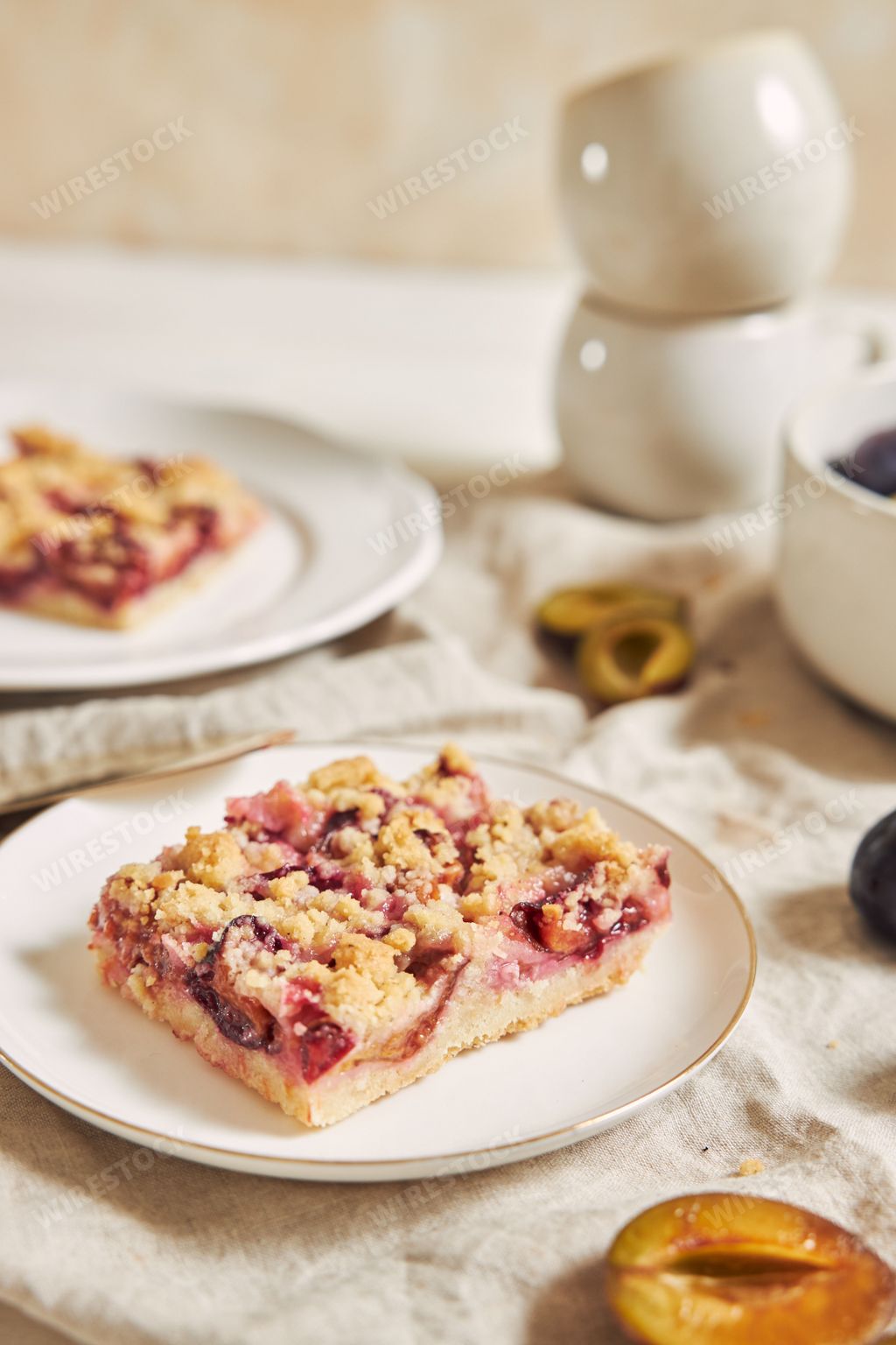 Delicious homemade plum cake with crumbles on plates on a white table