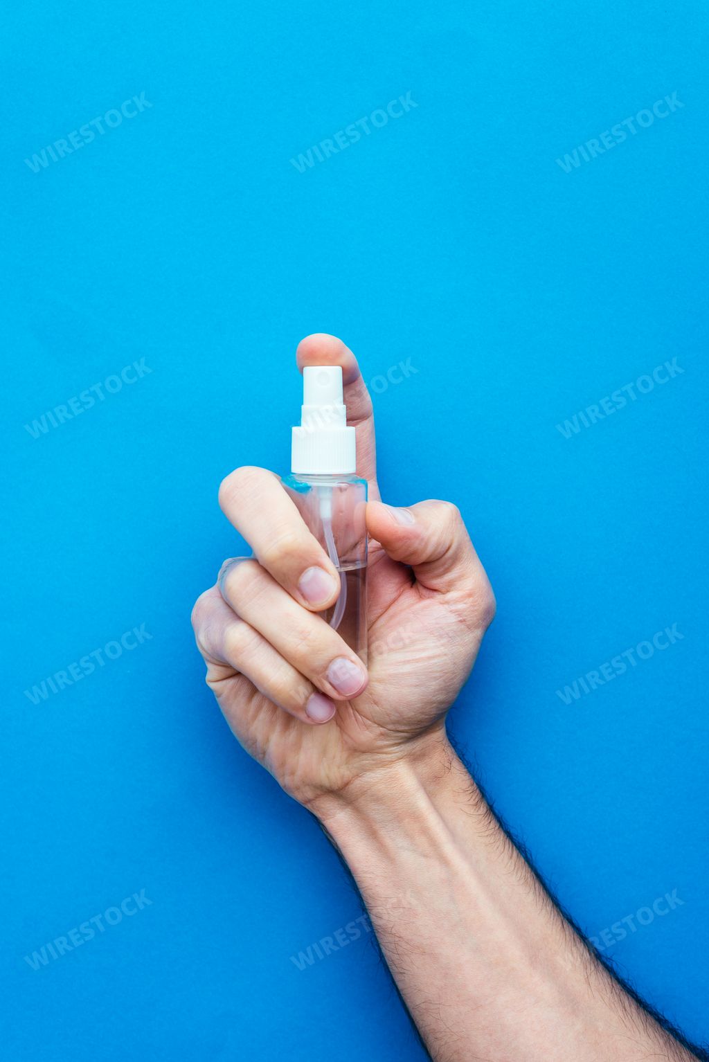 A vertical shot of a person's hand holding a bottle of sanitizer