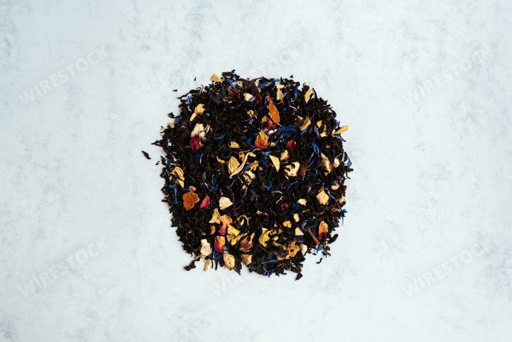 A top view shot of black tea mixed with flower petals on a light background with copy space.