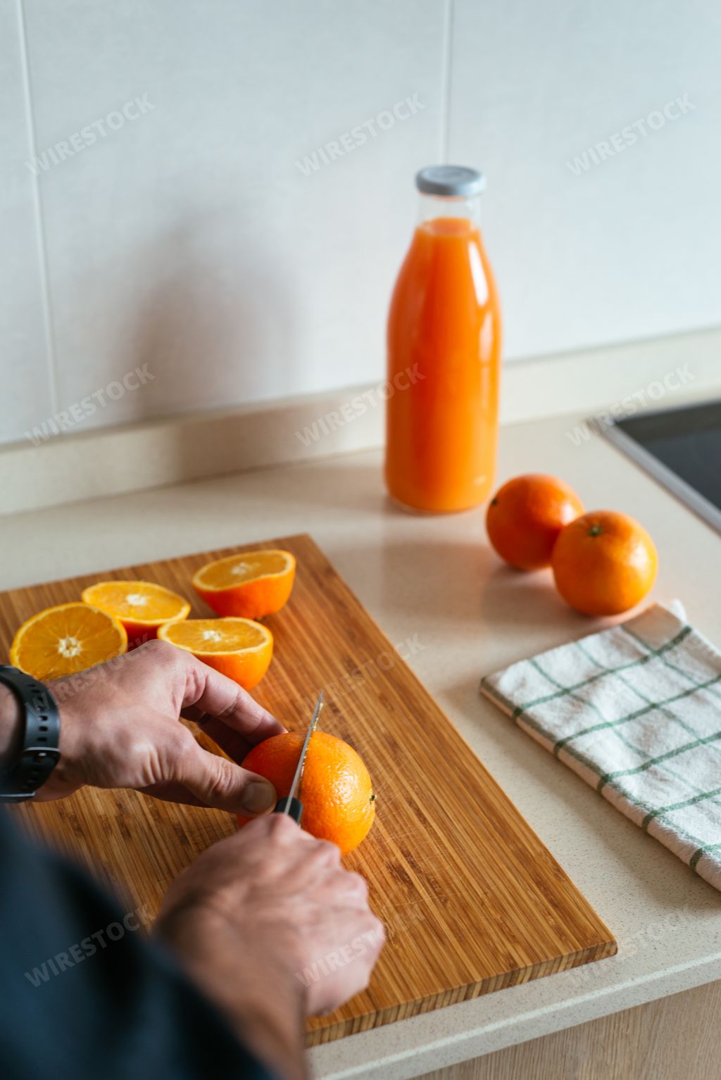 A vertical shot of male hands cutting oranges to squeeze