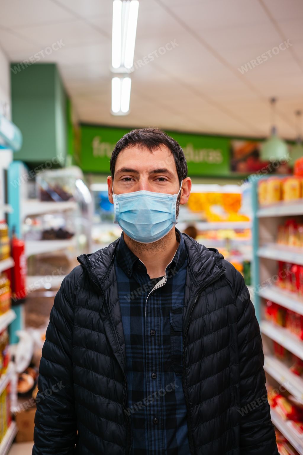 A Caucasian man wearing a face mask while he's at a supermarket - coronavirus concept