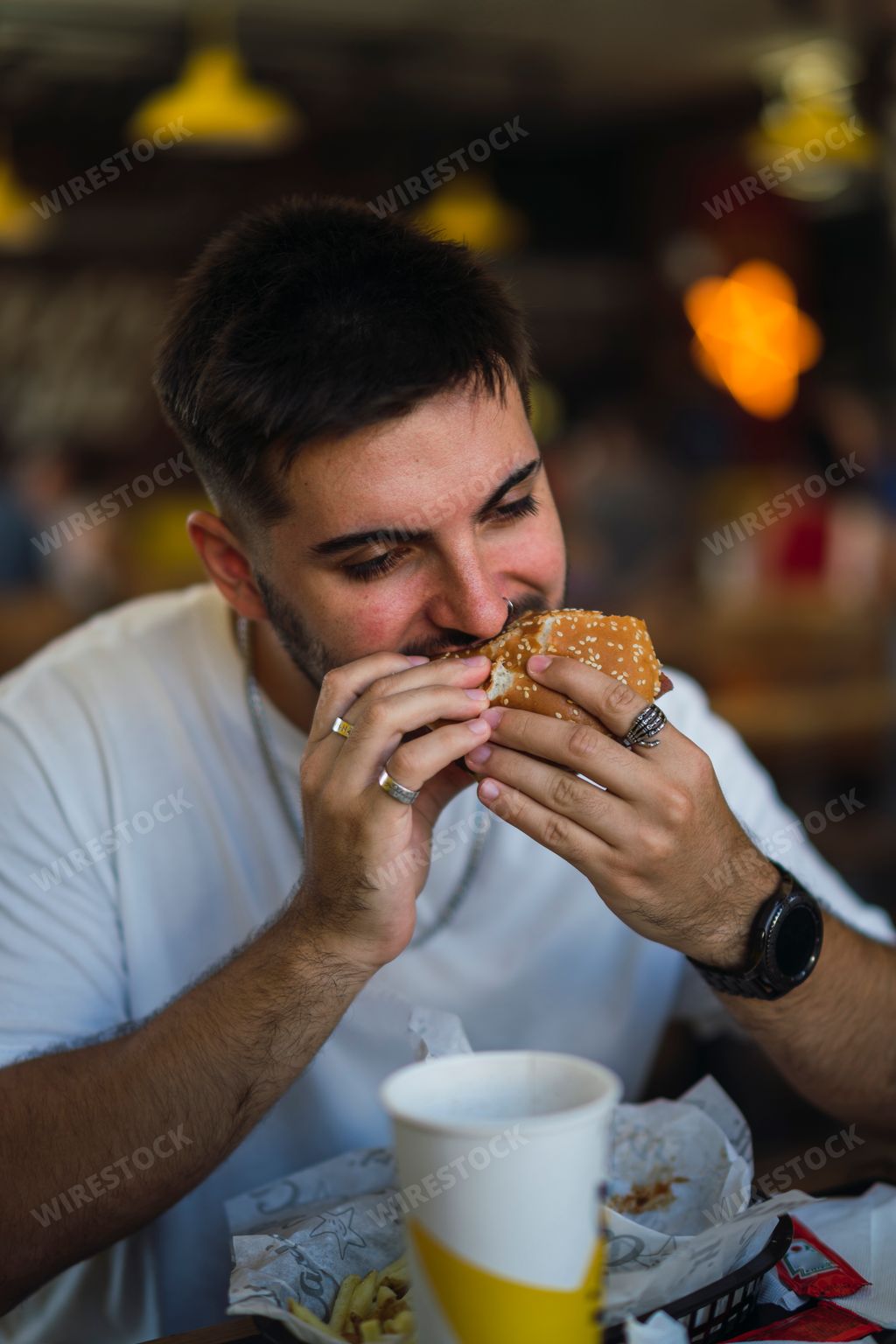 A vertical shot of a young caucasian male eating fast food sitting at the table