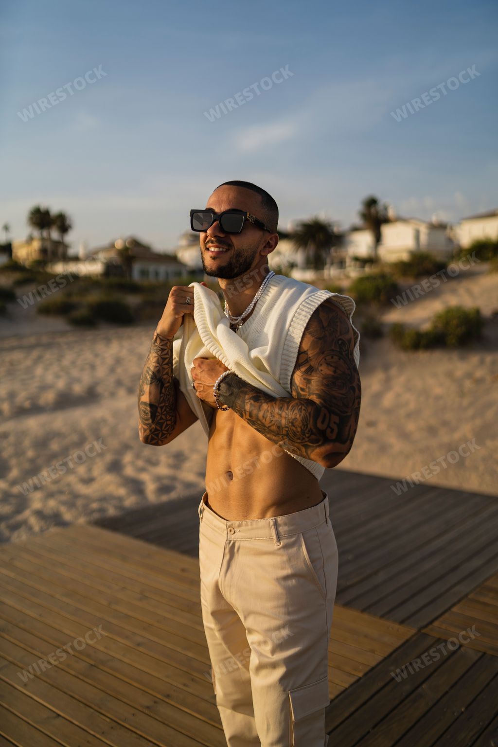 A vertical shot of a young tattooed man showing his abs