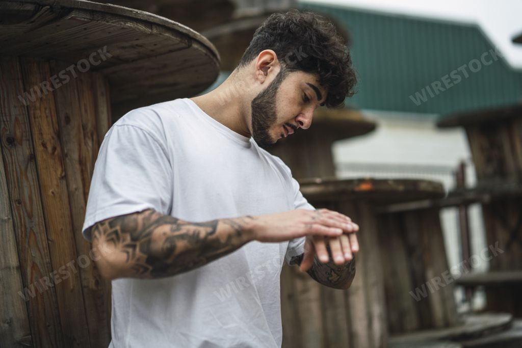 A cool European bearded male with arm tattoos touching his hand