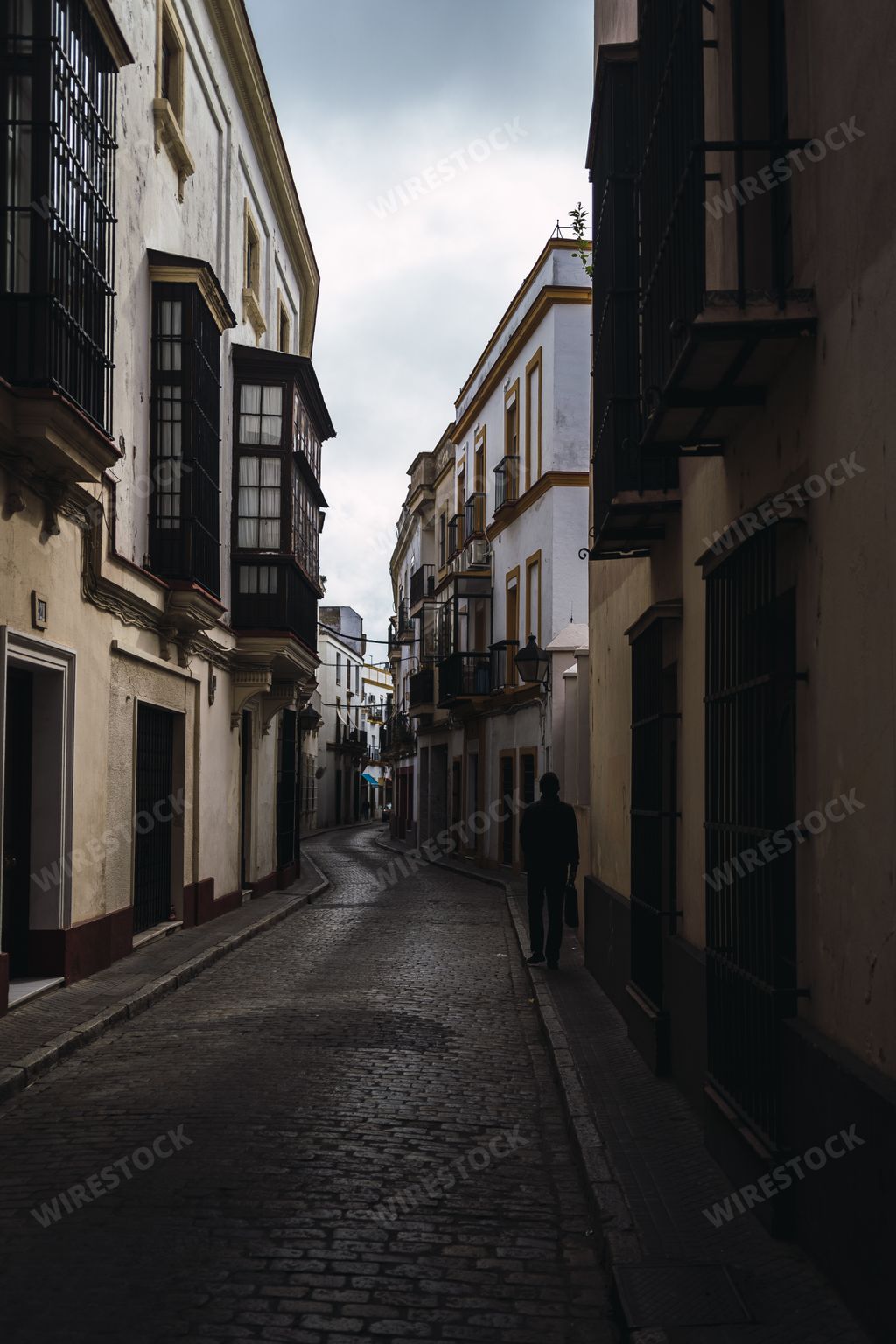 A vertical shot of a person walking through narrow buildings