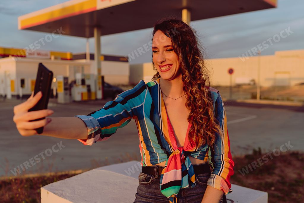 A closeup of an attractive woman taking a selfie at a gas station
