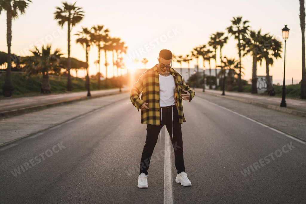 A stylish European man standing in a middle of a road at sunset