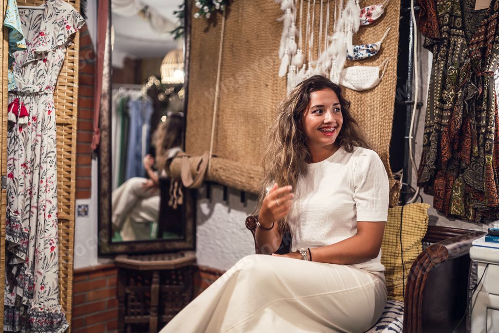 A happy tanned Caucasian female sitting in a shop  at an amusement park