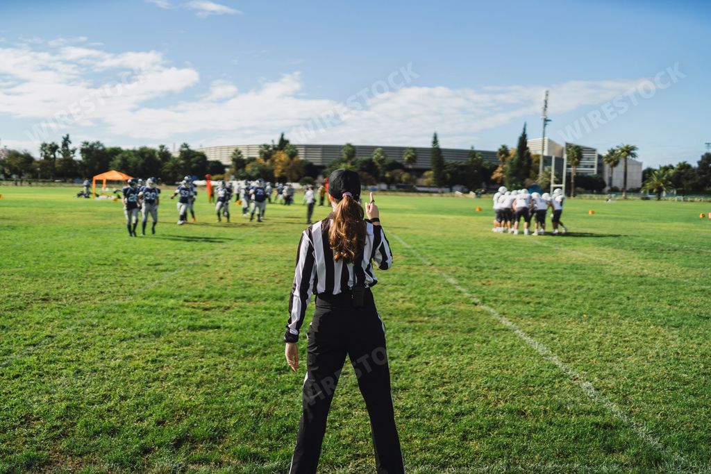 An American football referee standing on the field watching the game.
