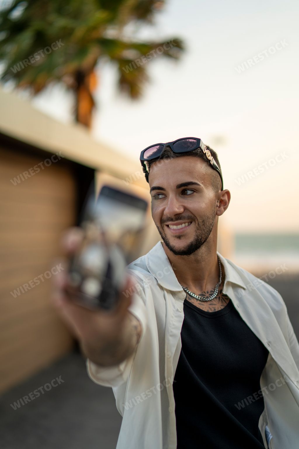 An attractive young Spanish bearded male in stylish clothes taking a selfie with a smartphone